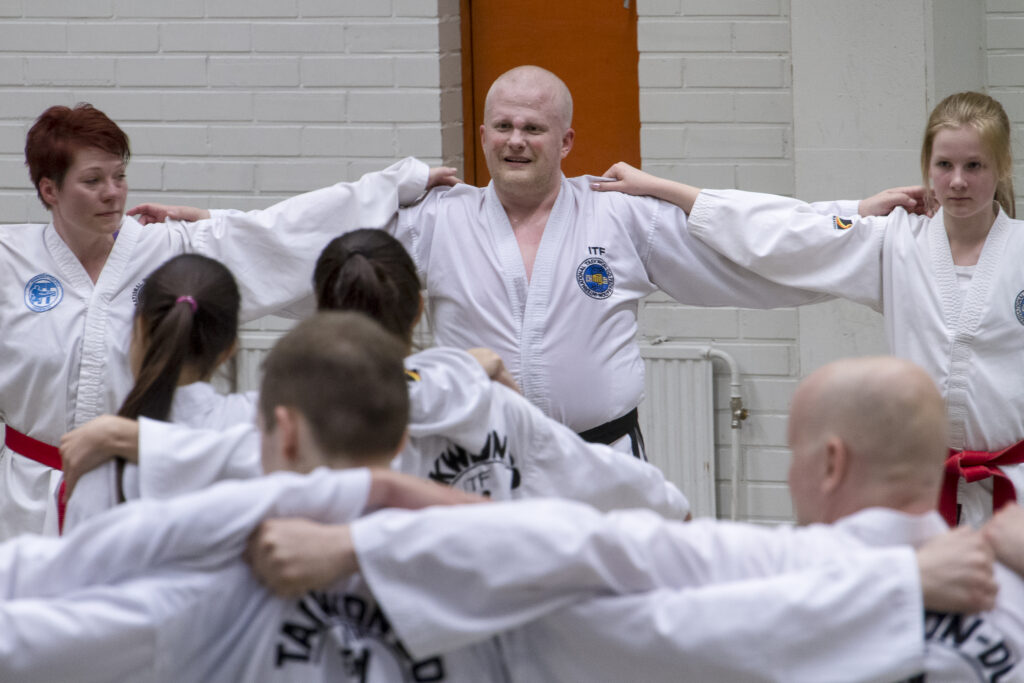 Harrastajat piirissä kädet toistensa harteilla